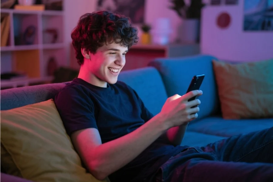 一名年轻玩家手持智能手机，在舒适的休闲环境中轻松操作软件，神情愉悦